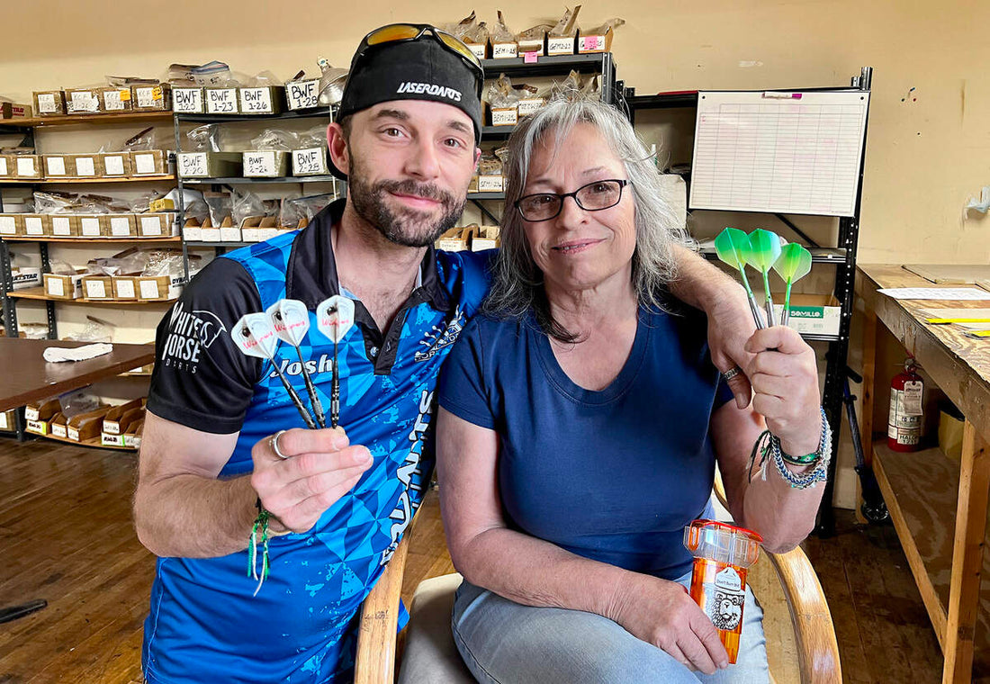Two of the Horizon Darts team holding finished darts in the Kansas City workshop, stock shelves behind them